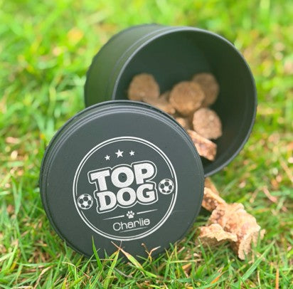 Black container labeled 'Top Dog' with dog treats on a grassy background